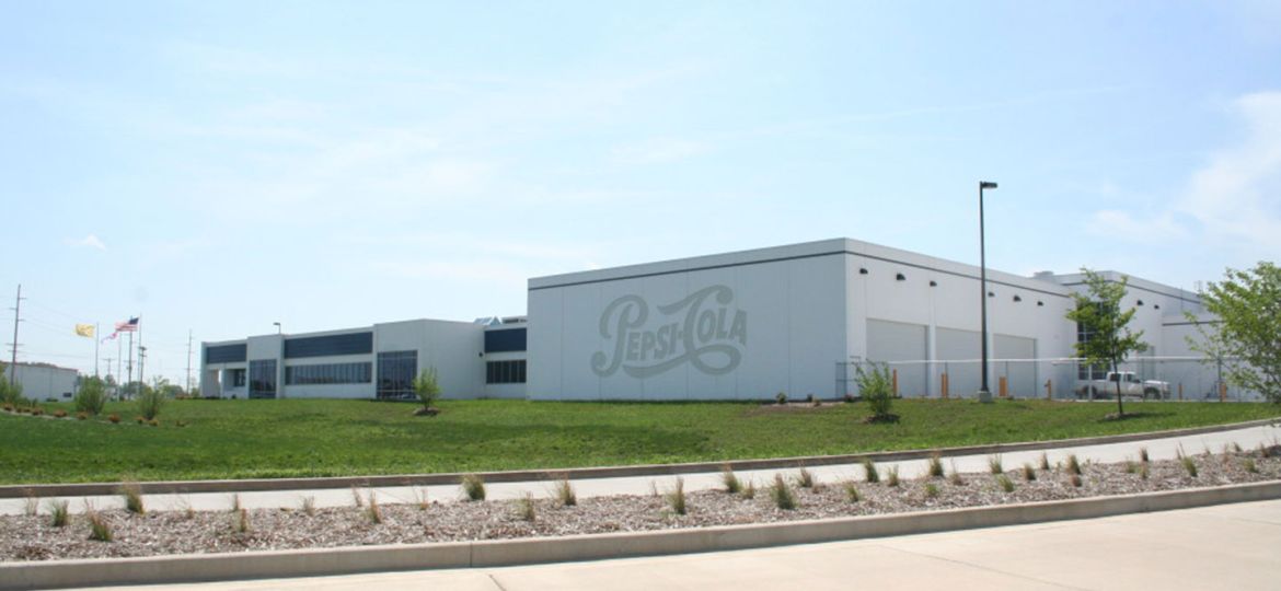 Exterior view from drive of Pepsi-Cola facility with large logo embedded in precast
